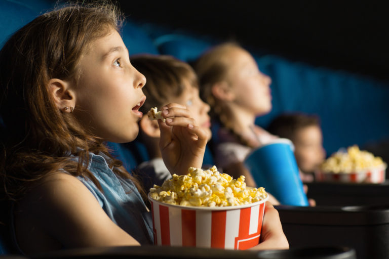 Beautiful,Little,Girl,Looking,Fascinated,Eating,Popcorn,Watching,A,Movie